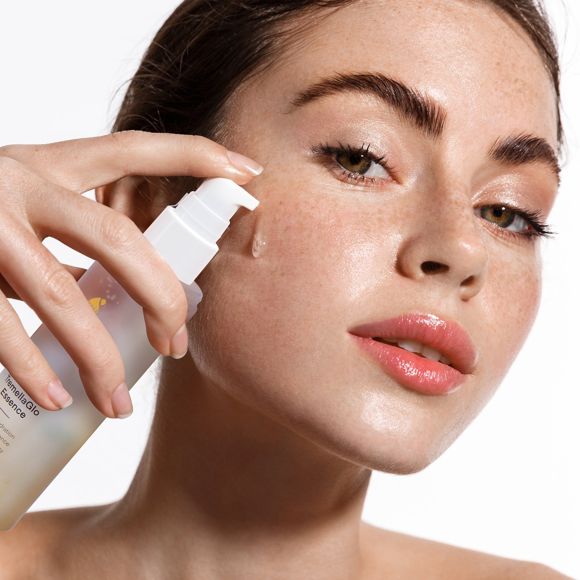 Woman applying Terez & Honor TremellaGlo Essence for glowing, hydrated skin.