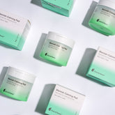 Multiple jars and boxes of Terez & Honor Blemish Calming Pads arranged in an aesthetically pleasing pattern on a bright background, emphasizing the clean, clinical design of the skincare product packaging.